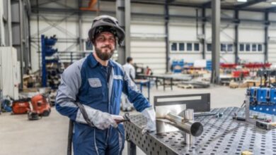 portrait of male welder holding welding torch in factory